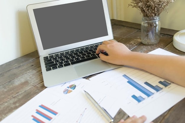 A person meticulously organizing notes and presentation slides on a desk, with a laptop displaying research data.