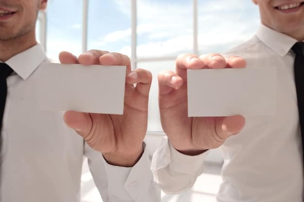 A close-up shot of two hands exchanging business cards. The focus is on the act of giving and receiving, symbolizing the core of reciprocity in networking. The background is blurred, but suggests a professional conference or networking event.