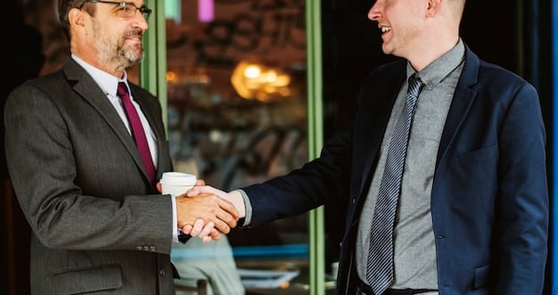 A close-up shot of two professionals shaking hands at a networking event, symbolizing trust and a mutually beneficial connection. The background is blurred with other attendees, emphasizing the focused interaction between the two individuals.