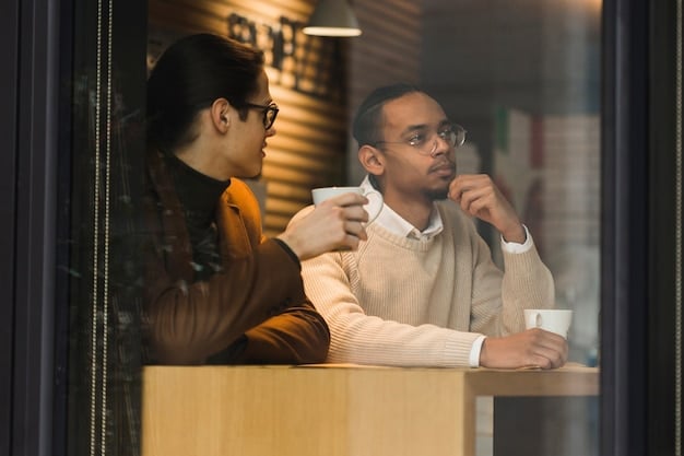 A mentor and mentee sitting in a coffee shop, engaged in a deep conversation, both looking attentive and involved.