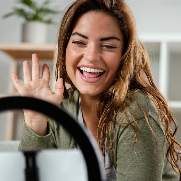 A close-up of a person smiling genuinely while engaged in a video call on their laptop. The background is blurred but suggests a home office environment. The focus is on conveying authenticity and connection through digital communication.